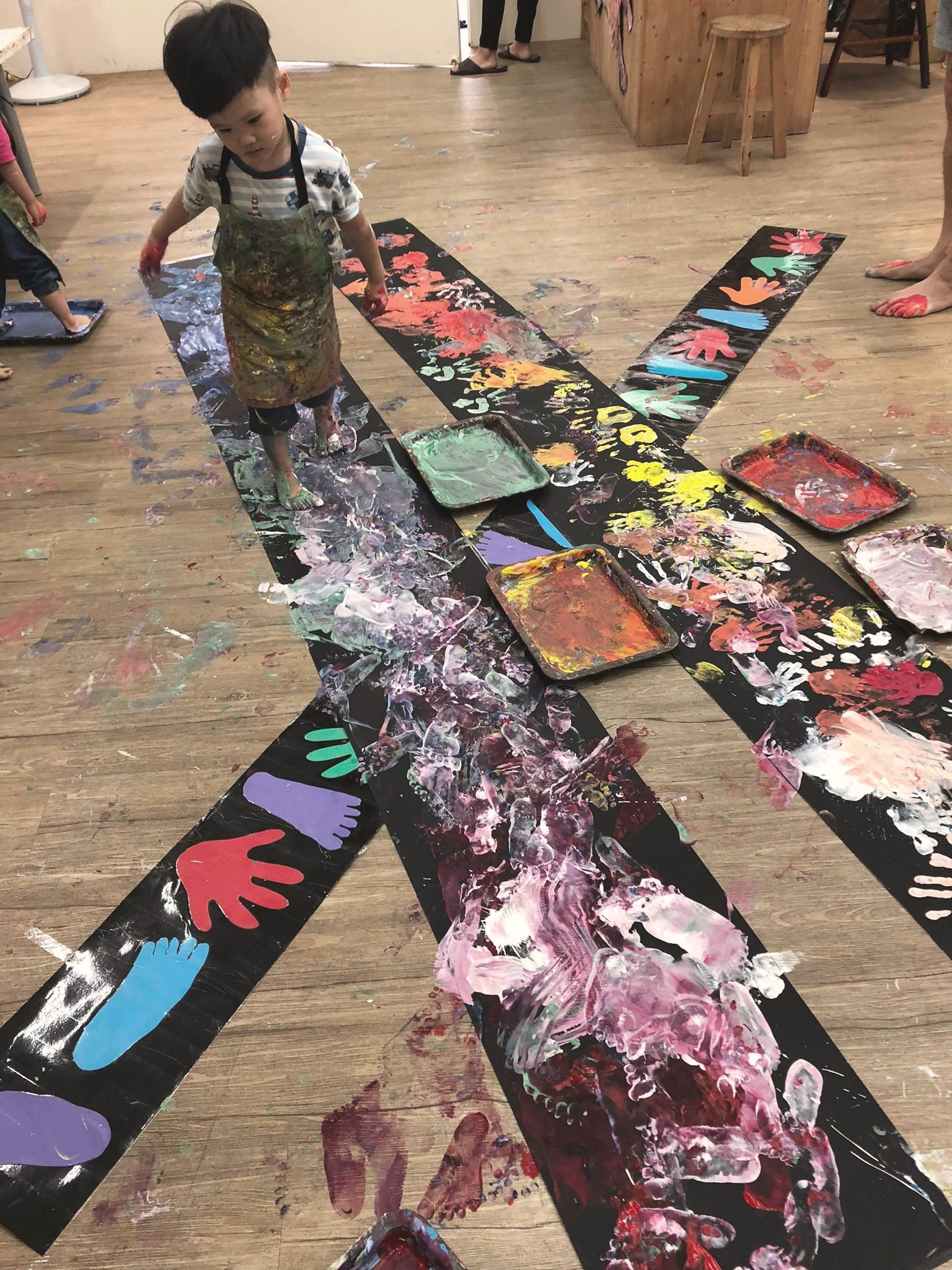 孩子用身體與手腳在大型黑紙上創作