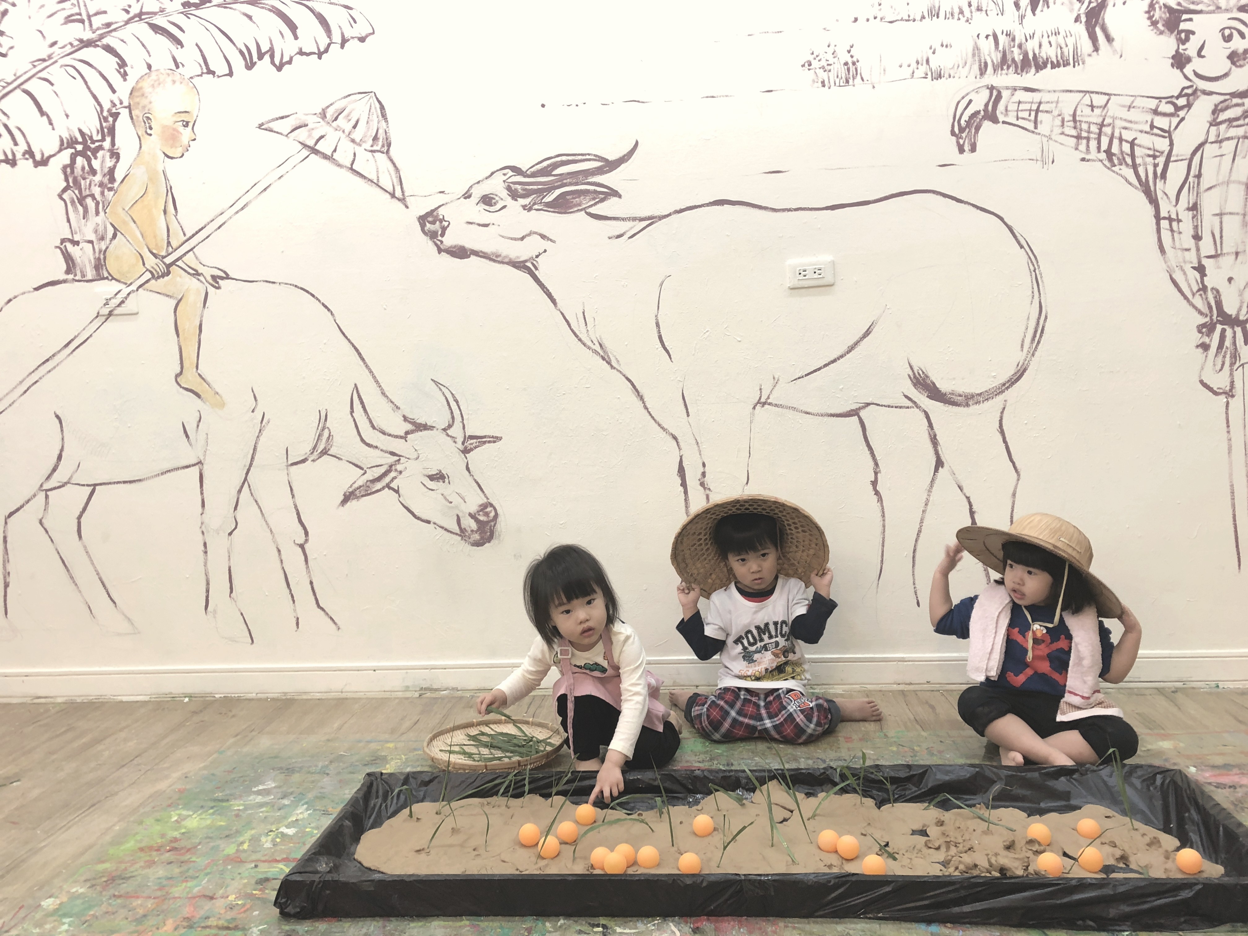 孩子們戴斗笠在水牛壁畫前進行在地文化課程