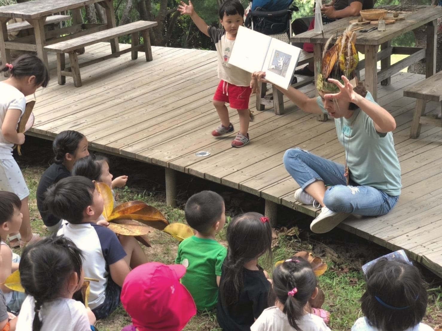 孩子們在戶外聽老師說繪本故事並觀察自然材料